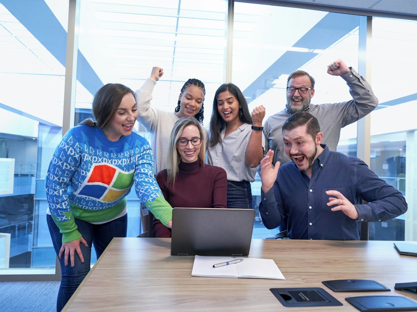 An office team cheering around a laptop